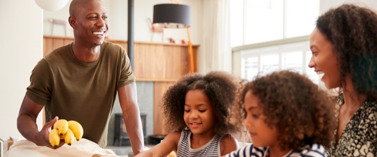 Family Returning Home From Shopping Trip Unpacking Plastic Free Grocery Bags