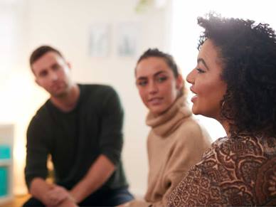 A woman talking infront of a man and woman