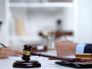 A gavel rests on the table whilst two people are sat opposite each other talking