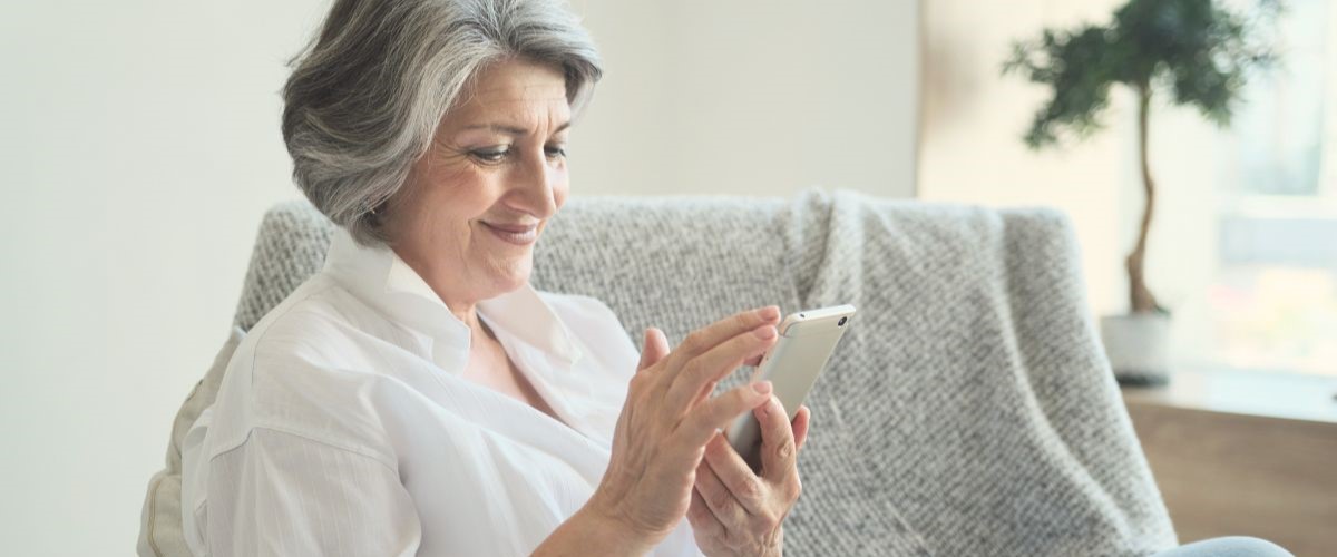 mature woman looking at phone on sofa