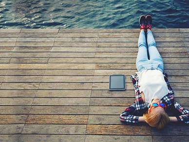 lying by the sea with an ipad