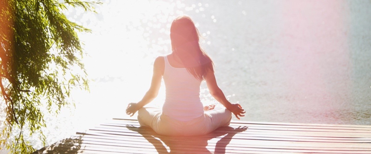 women meditating on decking with sea view