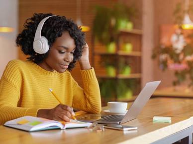 Woman listening to music whilst writing in a notebook