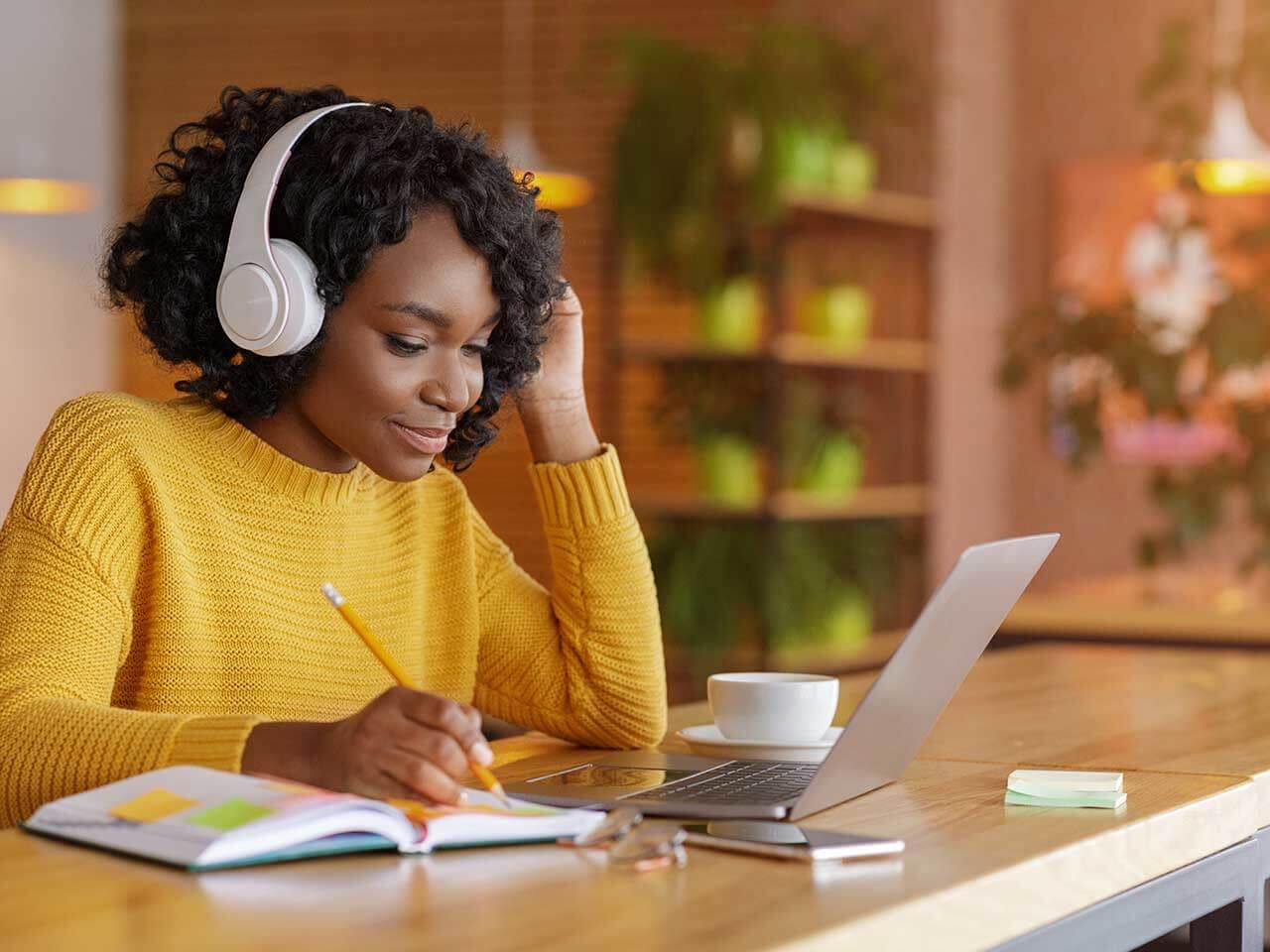 Woman listening to music whilst writing in a notebook