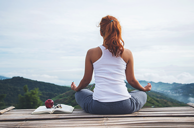 Woman meditating overlooking hills